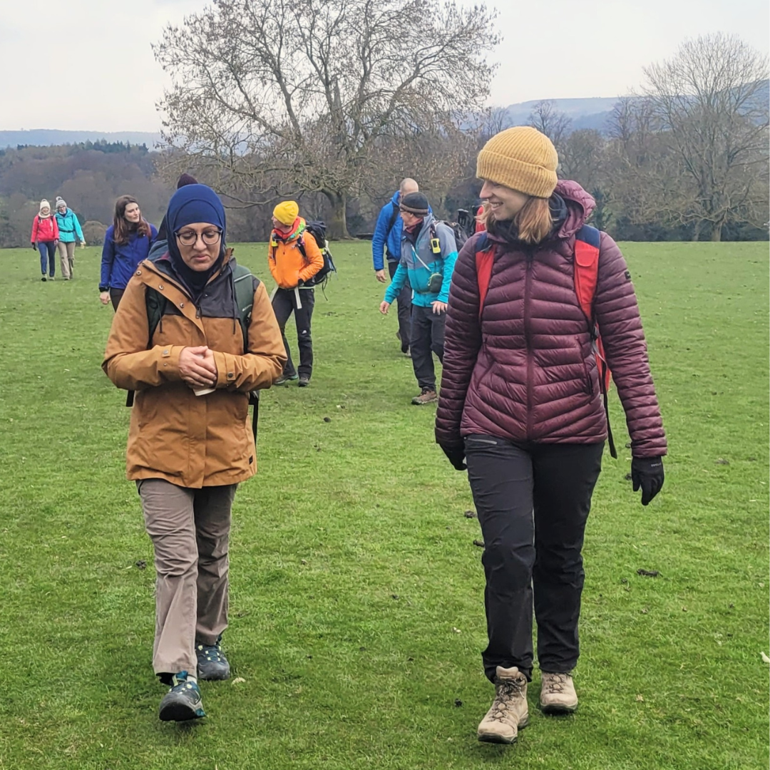 Hiking group - two women at front talking on mental wellness walk and talk