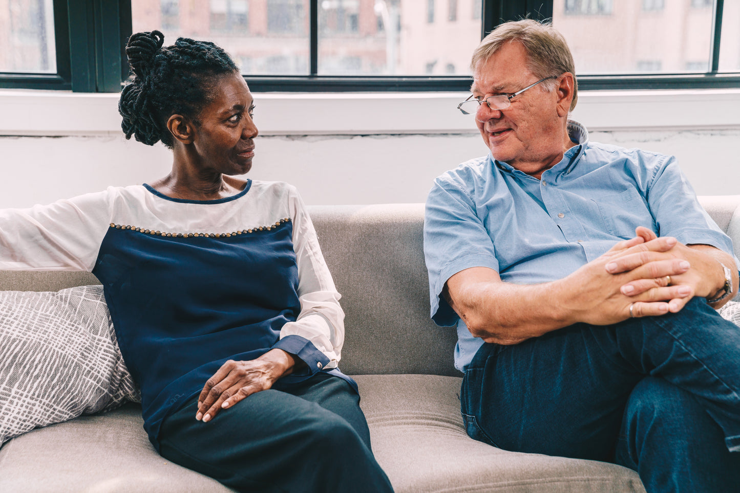 woman and man seated talking to each other on sofa