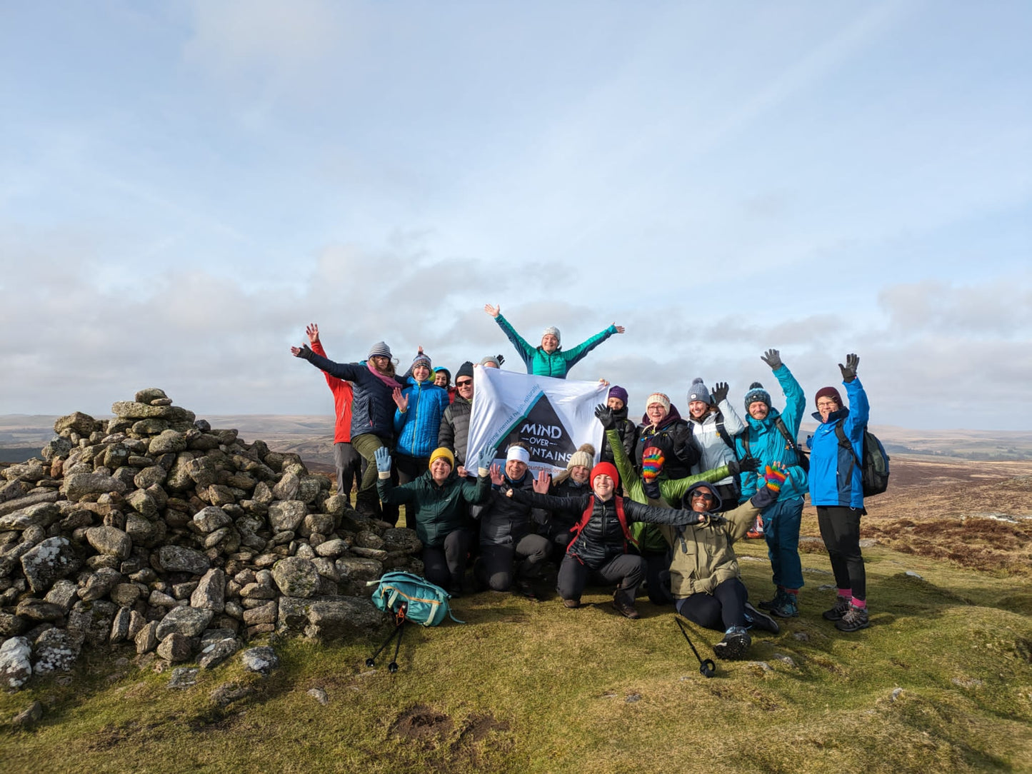 Group of hikers celebrating summit during mental wellbeing retreat 