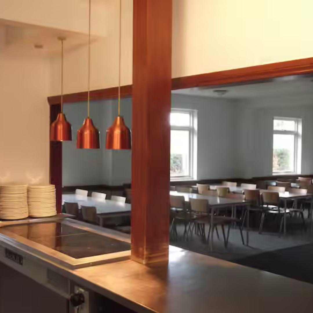 Restaurant interior with tables, chairs, and copper pendant lights.