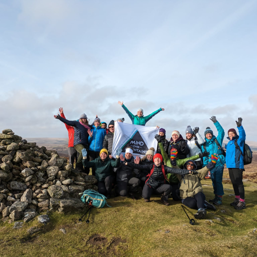 Group of people posing with a Mind banner on a mountain top