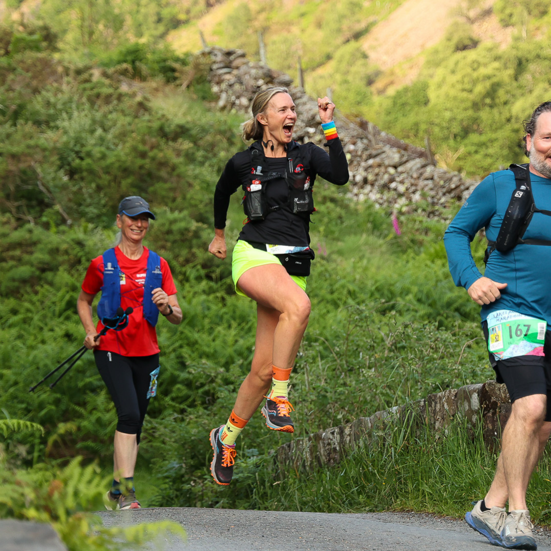 Three runners on a trail with greenery in the background