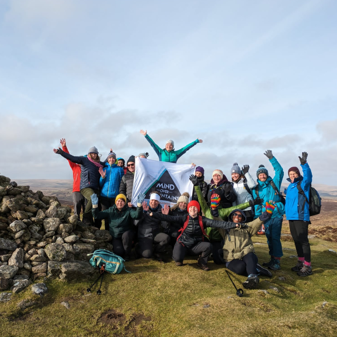 Group of people posing with a banner on a mountainous landscape