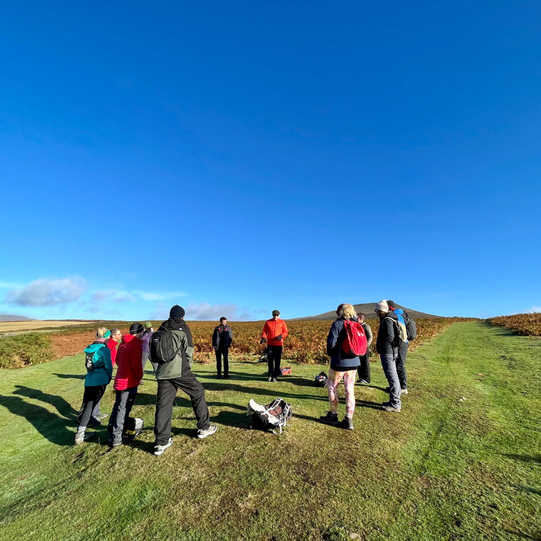 Group of people standing on a grassy field with a clear blue sky