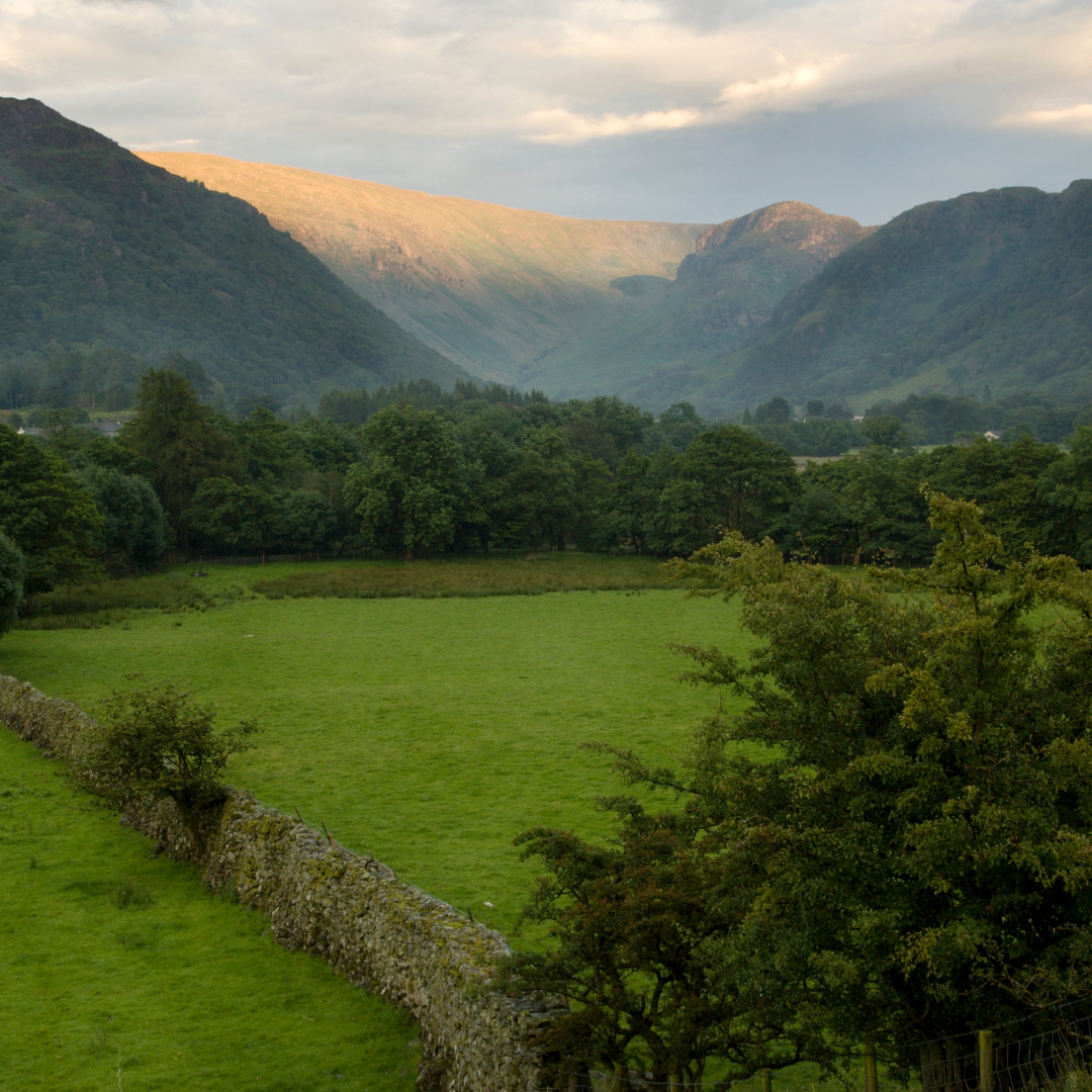 Valley with green fields and mountains under a cloudy sky