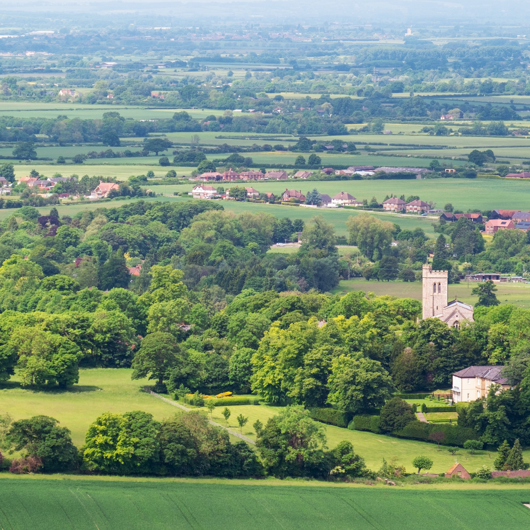 Aerial view of a village surrounded by green fields and trees