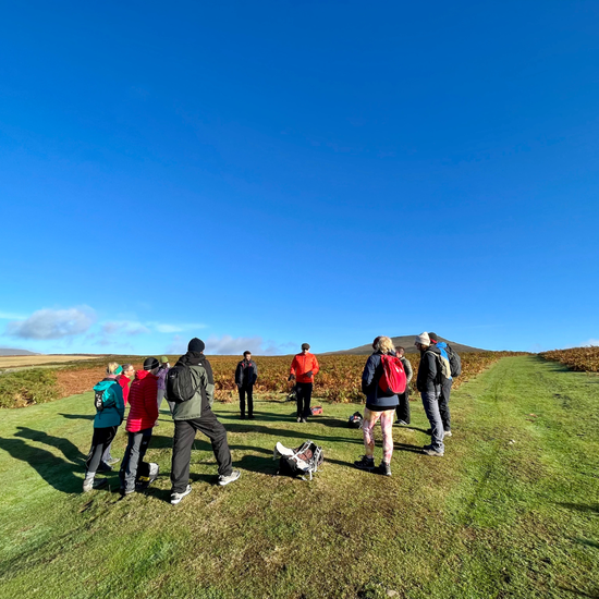 Group of people standing on a grassy field with a clear blue sky