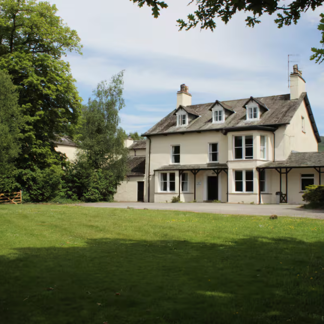Large house with a grassy lawn and trees in the background