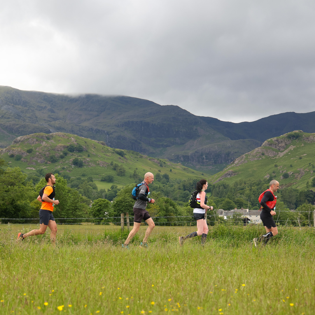 four people running against a scenic backdrop