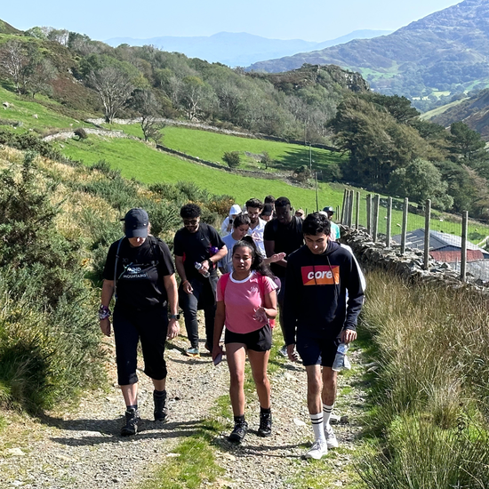 Group of people hiking on a trail with mountains in the background