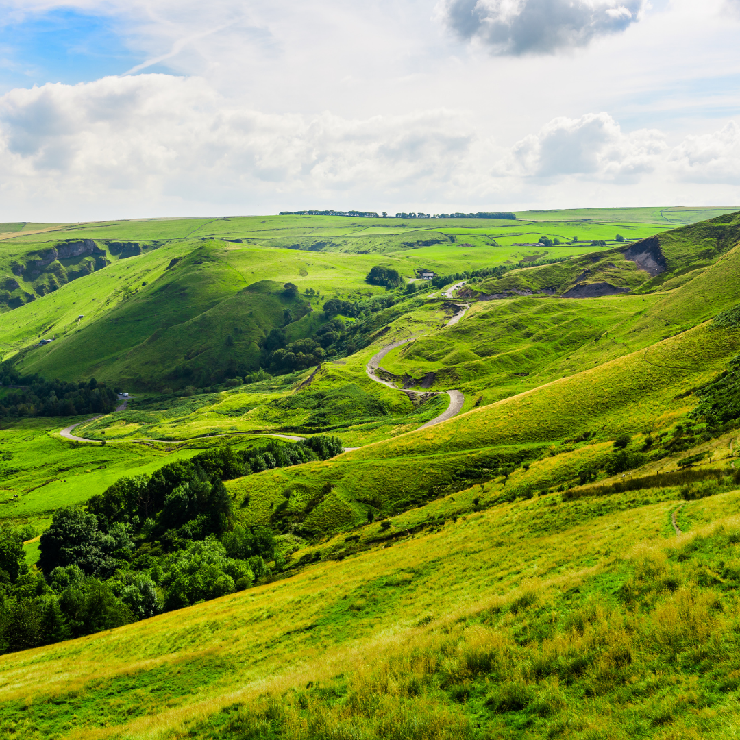 Green hills and valleys under a blue sky with clouds