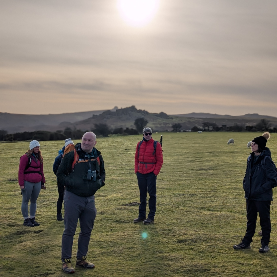 Group of people standing in a field with mountains in the background