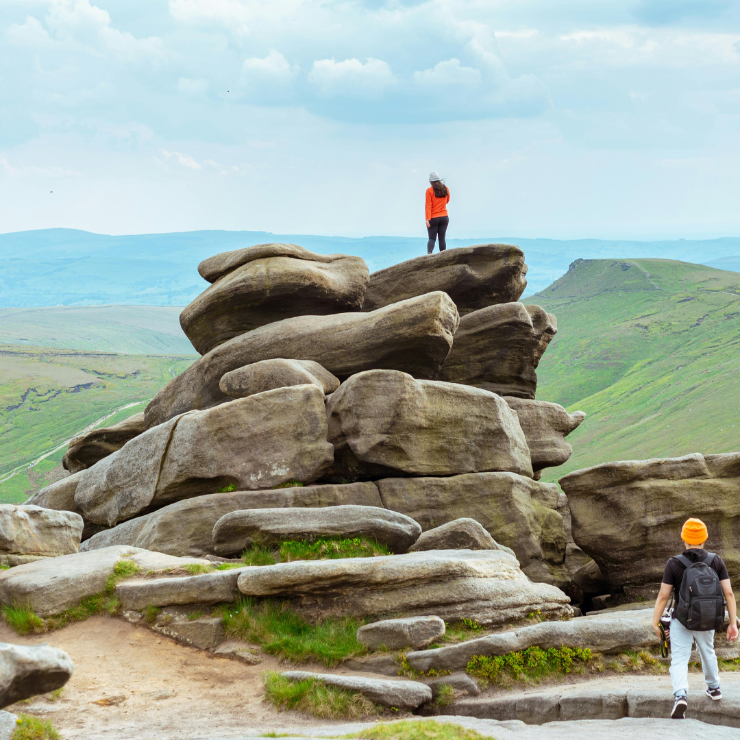 Two people standing on large rocks with a scenic landscape in the background