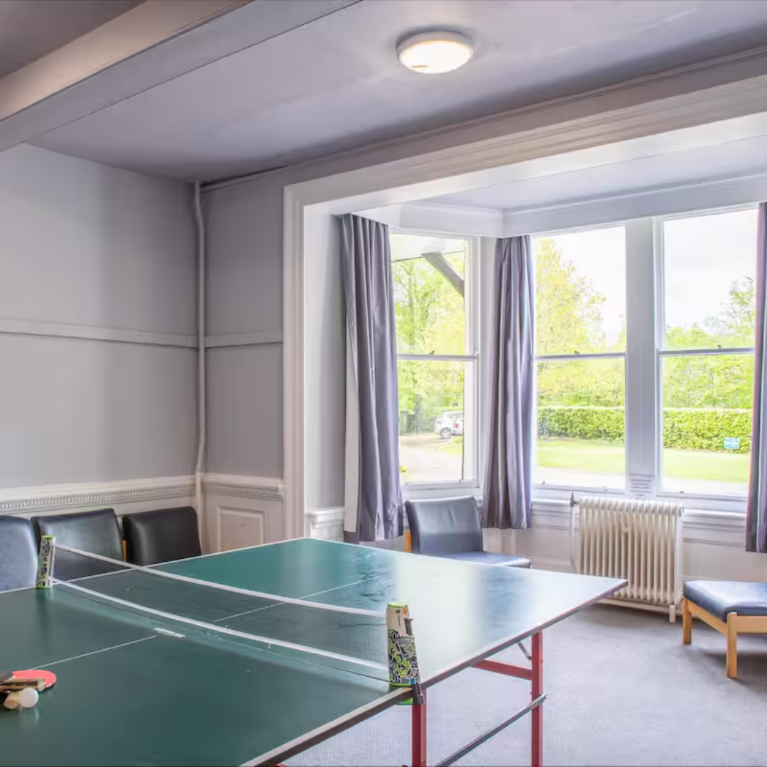 Ping pong table in a room with large windows and curtains
