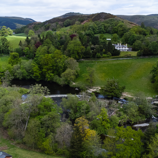green landscape in north wales with trees, horseshoe falls and Bryntysilio Hall amongst the trees