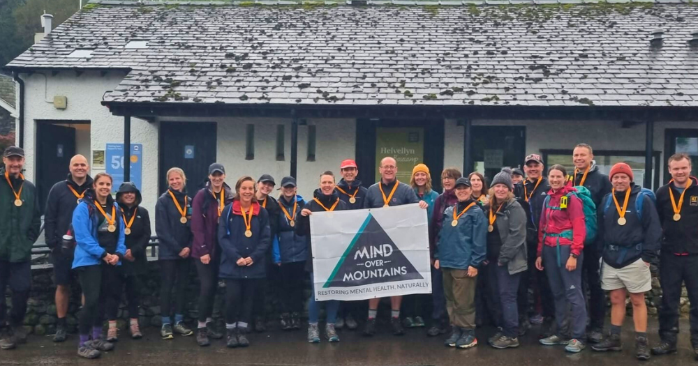 Charity fundraising group wearing wooden medals having completed hike to raise funds for Mind Over Mountains mental wellness charity