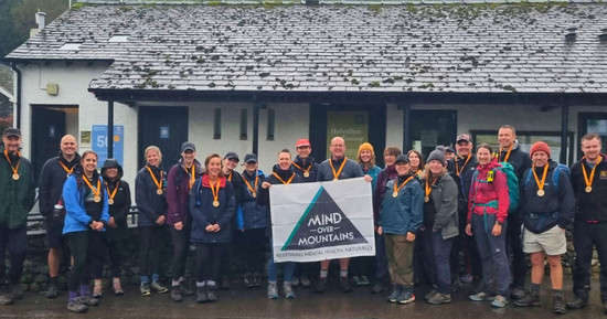 Charity fundraising group wearing wooden medals having completed hike to raise funds for Mind Over Mountains mental wellness charity