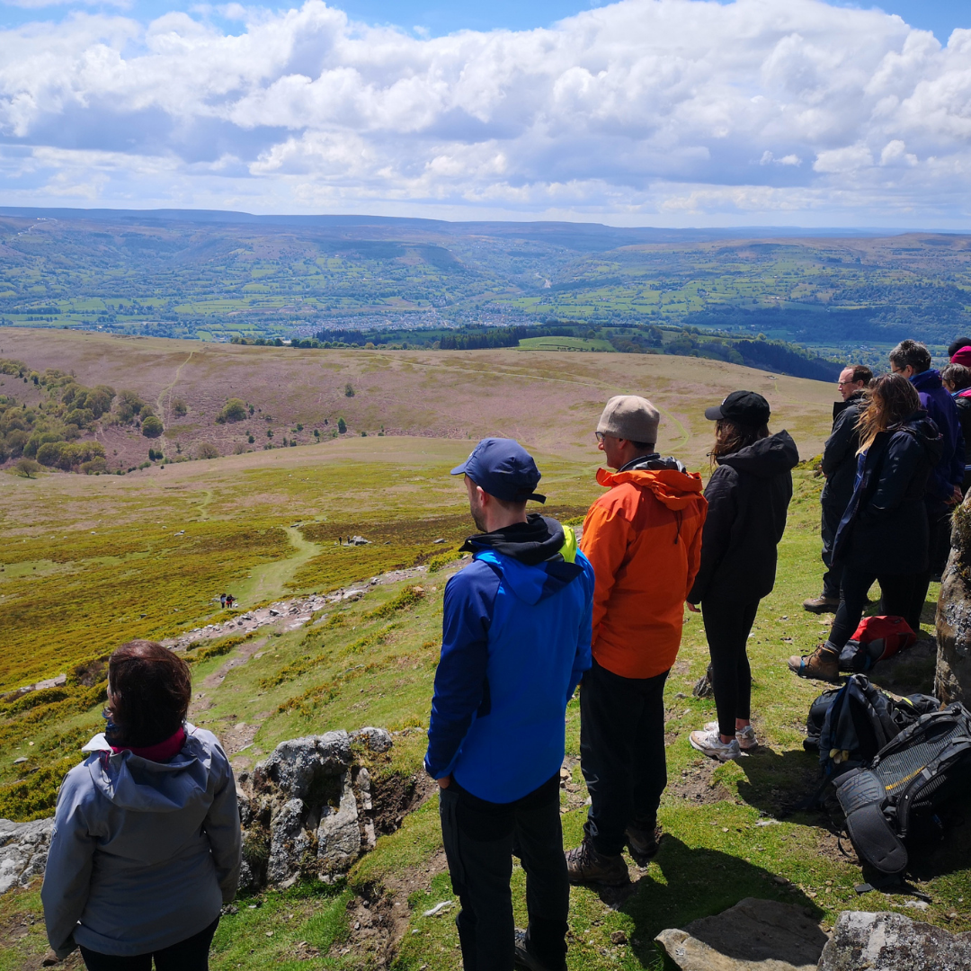 people practising mindfulness facing view of countryside