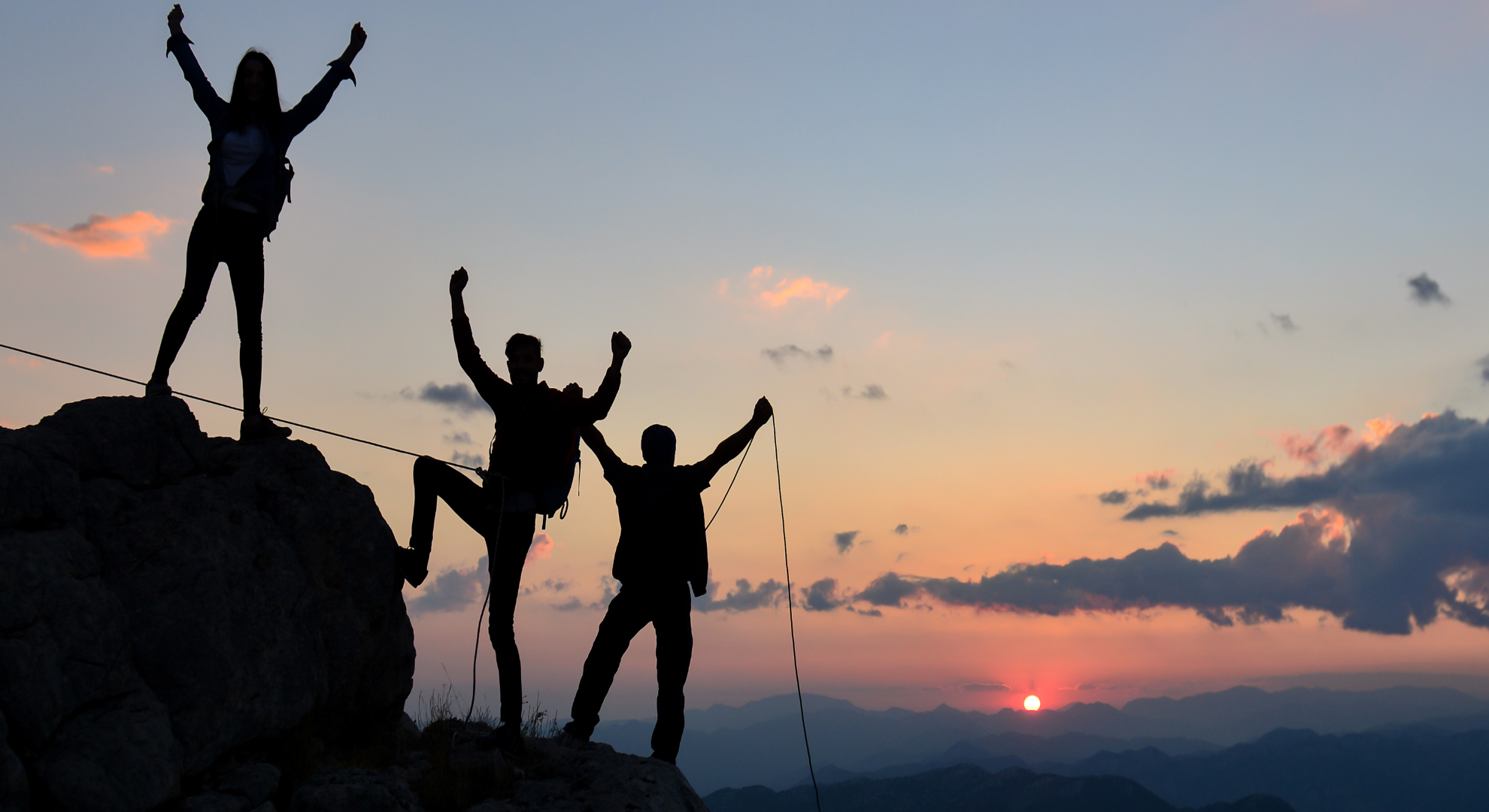 Walkers climbers at summit of mountain silhouetted against setting sun - celebrating summit with Mind Over Mountains Project 500 fundraiser