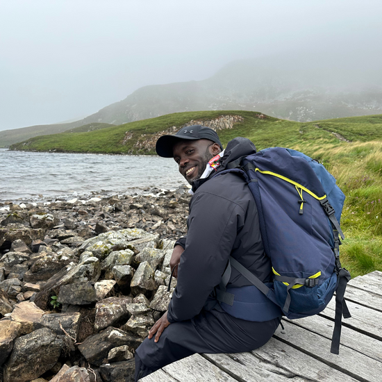 male hiker sitting by lake in Wales with rucksack