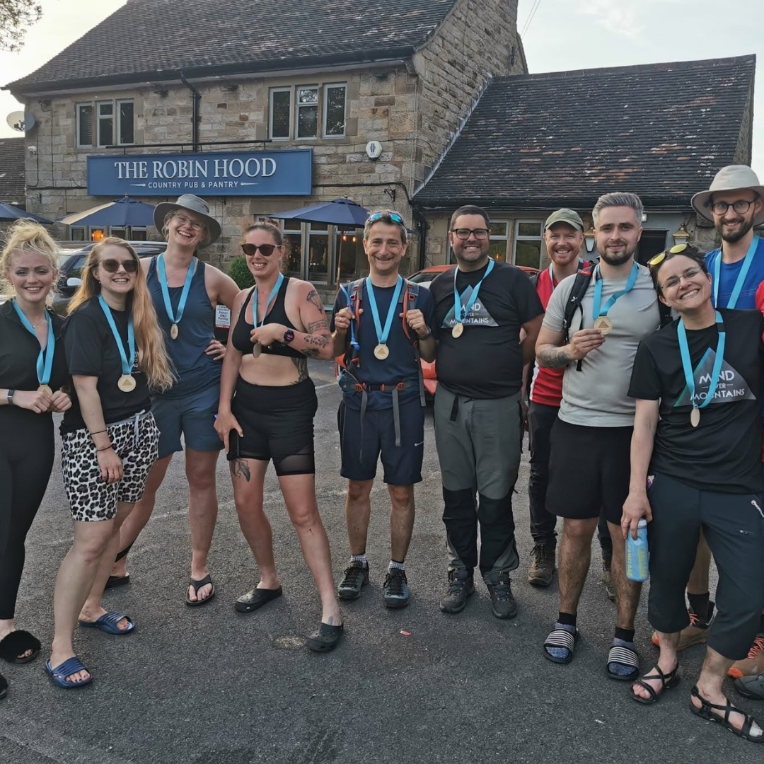 Group of runners with medals posing in front of 'The Robin Hood' pub.
