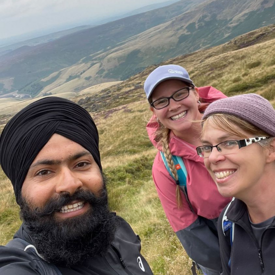group of three hikers selfie smiling during mental wellbeing walk 
